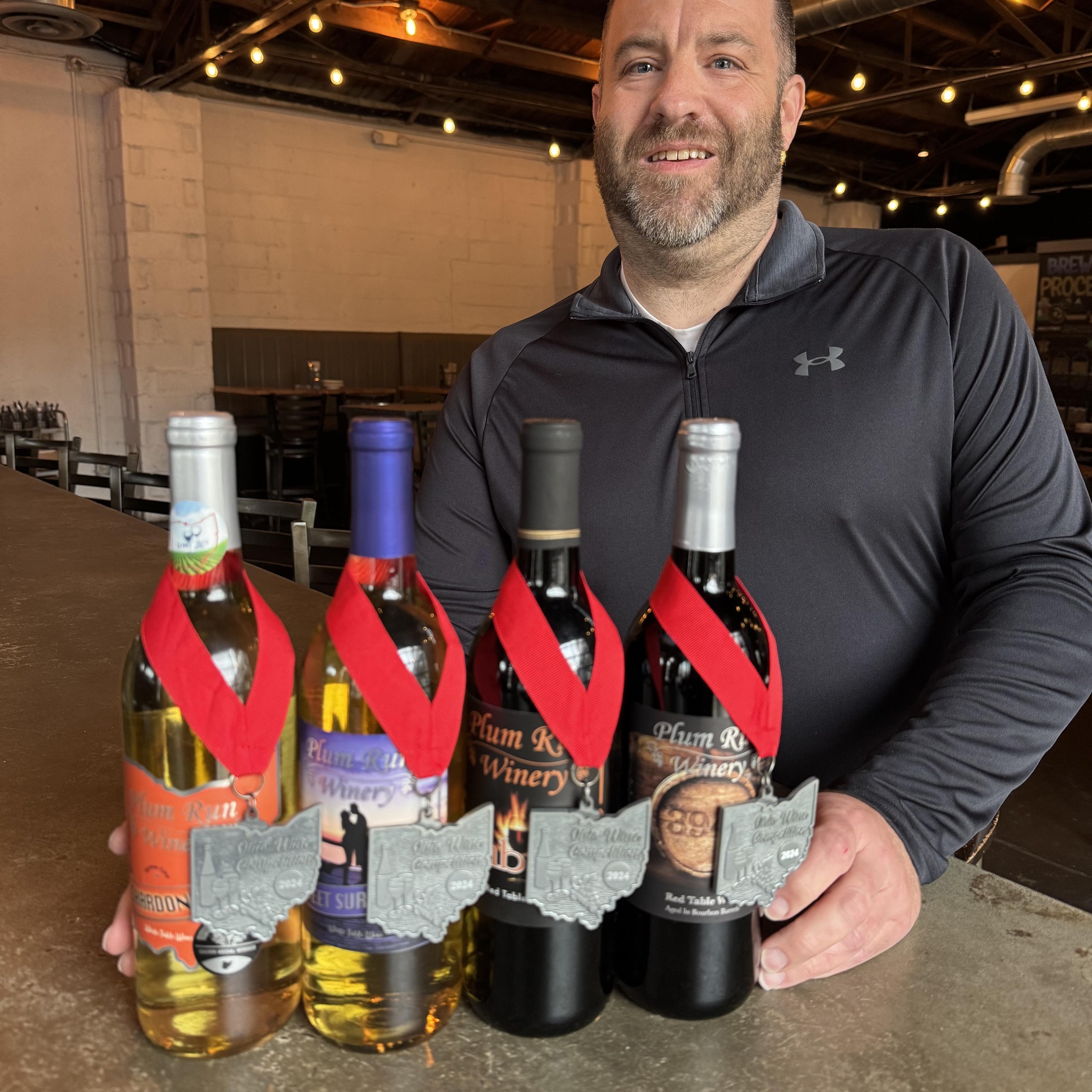Plum Run Winery winemaker Joe Weeks holding award-winning wines from the Ohio Wine Competition